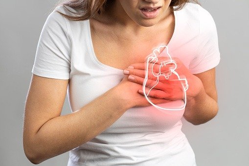 Young woman pressing on chest with painful expression. Severe heartache, having heart attack or cardiac arrest, heart disease.